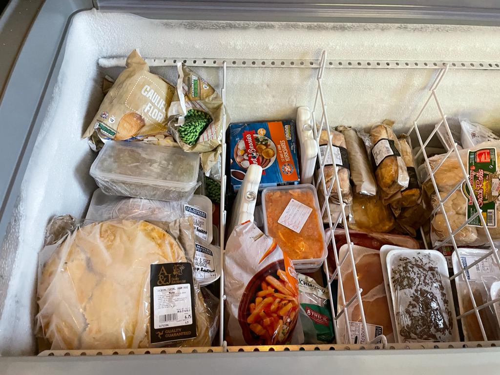 Shelves stocked with breads, milk, and vegetables