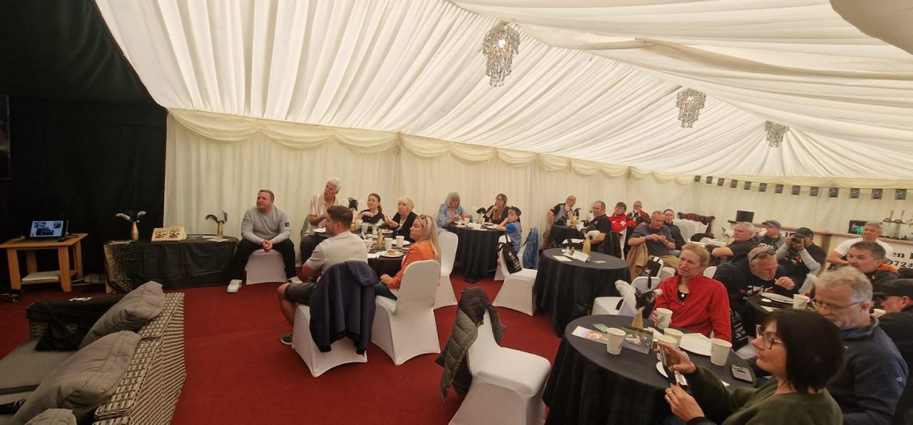 Attendees seated at tables during a TT hospitality event